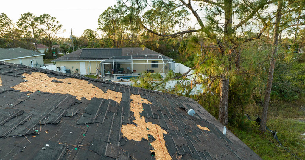 Hurricane-damaged home roof illustrating HOA insurance and windstorm coverage in Florida and Texas